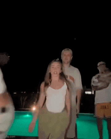 a woman is dancing in front of a swimming pool at night .