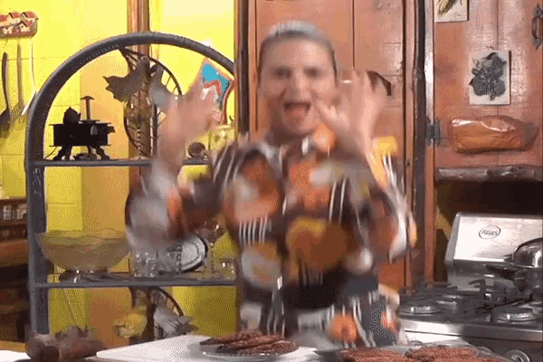 a woman in a colorful shirt is standing in front of a stove with a plate of food on it