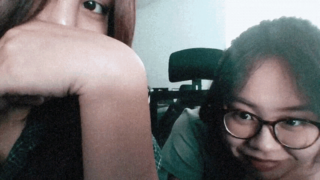 a woman wearing glasses covering her face with her hand next to another woman
