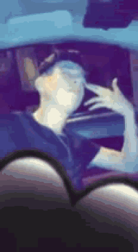 a man is sitting in the driver 's seat of a car making a peace sign .
