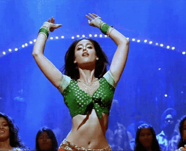 a woman in a green top is dancing on stage