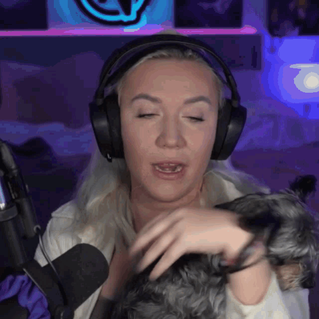 a woman wearing headphones and holding a small dog