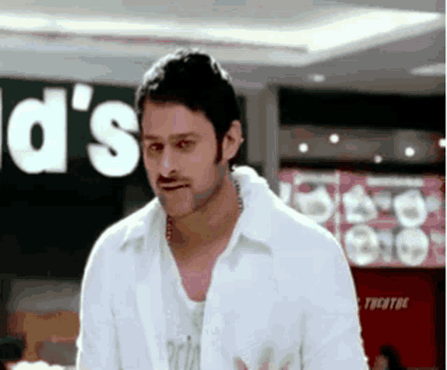 a man wearing a white shirt is standing in front of a mcdonald 's sign .