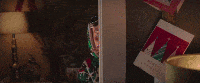 a man with a beard and goggles is peeking out of a doorway next to a christmas card .