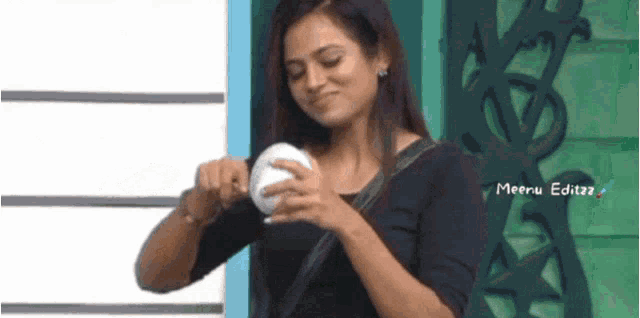 a woman in a black shirt is holding a white object .