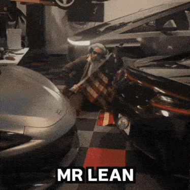 a man is holding an american flag in a garage with the name mr lean written above him