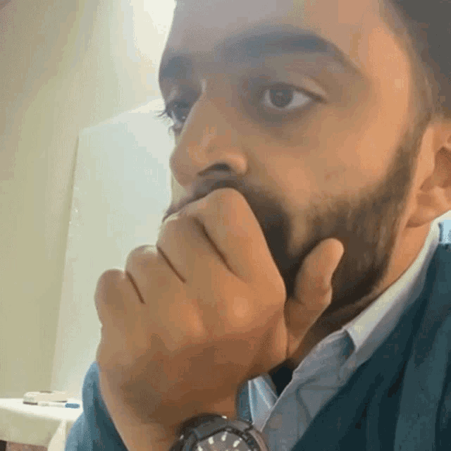 a man with a beard is covering his mouth with his hand