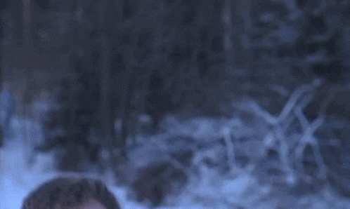 a man in a blue jacket stands in the snow with his mouth open