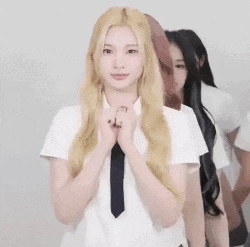 a woman with long blonde hair is wearing a white shirt and tie .