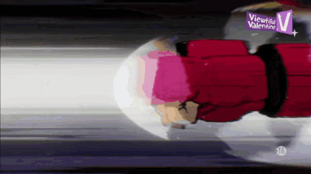 a man in a red jacket is flying through the air with a viewical valentine sign behind him