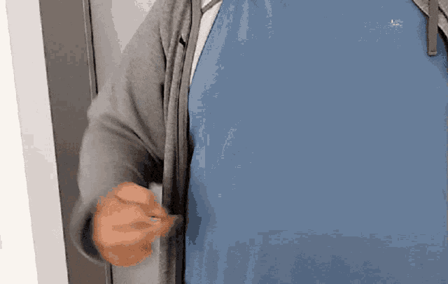 a man wearing a blue shirt and a grey hoodie is giving the middle finger