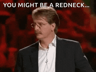 a man in a suit and glasses is standing in front of a red background and says `` you might be a redneck ... ''