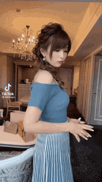 a woman in a blue off the shoulder top is standing in a living room