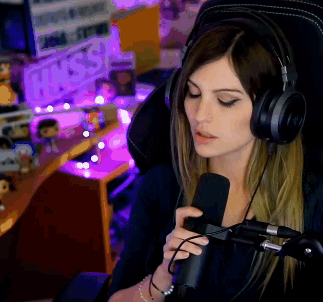 a woman is wearing headphones and holding a microphone in front of a sign that says ghosts