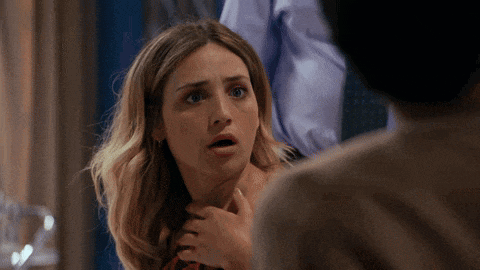 a woman with a surprised look on her face is holding a man 's neck