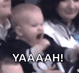 a baby is screaming in a crowd of people while sitting in a stadium .
