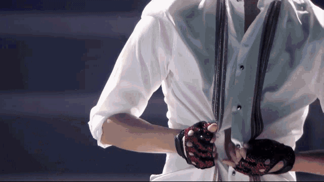 a man wearing a white shirt and red gloves holds his shirt open