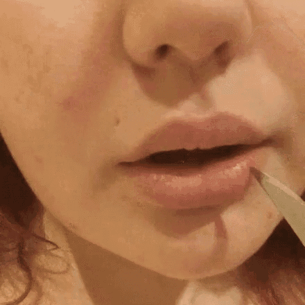 a woman is applying lipstick to her lips with a marker .