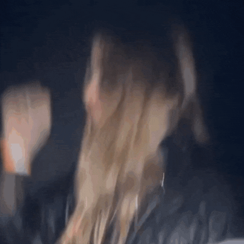a woman 's hair is blowing in the wind in a dark room