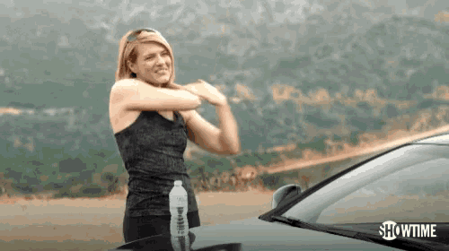 a woman is stretching her arms in front of a car with showtime written on the bottom