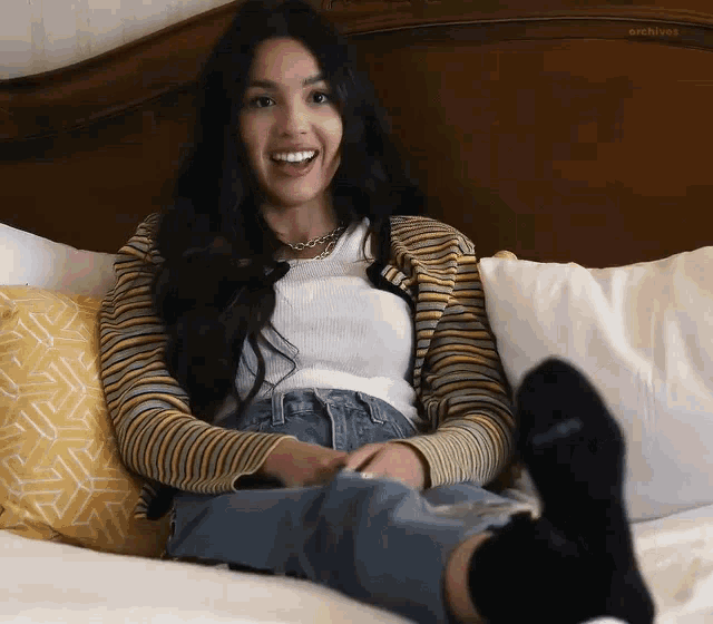 a woman is laying on a bed with her feet up and smiling