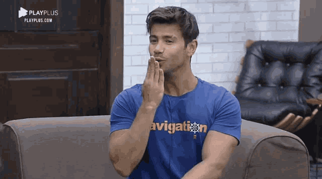 a man sitting on a couch wearing a blue shirt that says aviation