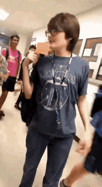 a boy wearing a rolling stones t-shirt is walking in a hallway