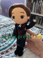 a person is holding a crocheted doll with the words je suis pret written on it