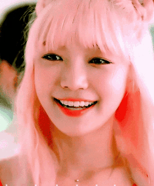 a close up of a woman 's face with pink hair smiling