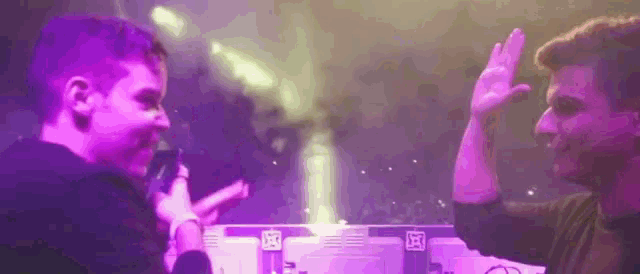 two men are giving each other a high five in front of a microphone .