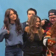 a group of people are standing next to each other in front of a blue wall .