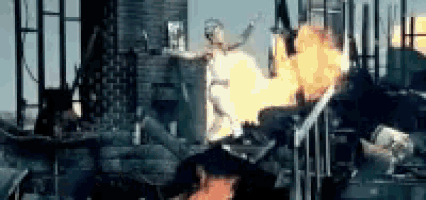 a statue of a woman is standing in front of a building with fire coming out of it .