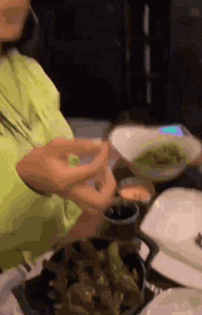 a woman is sitting at a table with a bowl of food and a phone .