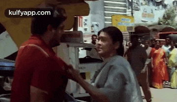 a man and a woman are standing next to each other on a street and talking to each other .
