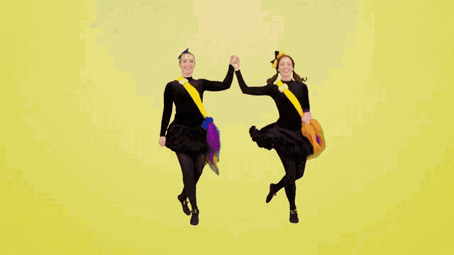 two girls are jumping in the air with their hands in the air