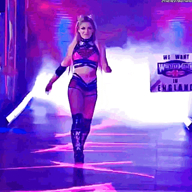 a female wrestler is walking down a stage with a sign behind her that says we want world heavyweight in england
