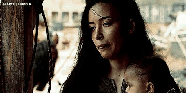 a woman is holding a baby in her arms and looking at it .