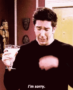a man in a black shirt is holding a martini glass and saying i 'm sorry