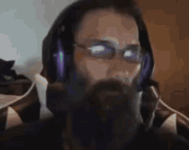 a man with glasses and a beard is wearing headphones .