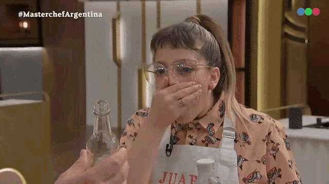 a woman covering her mouth while wearing an apron that says juan on it