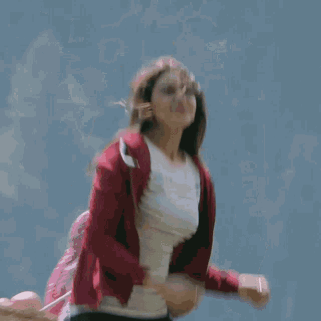 a woman wearing a red jacket and a striped shirt is running