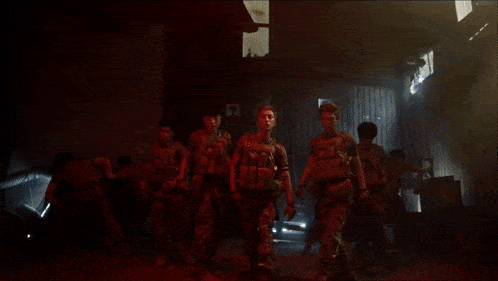 a group of soldiers are walking in a dark room with red lights