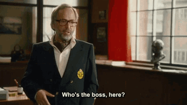 a man in a suit and tie is asking who 's the boss , here .