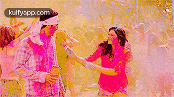 a woman is kissing a man on the cheek while he is covered in holi powder .
