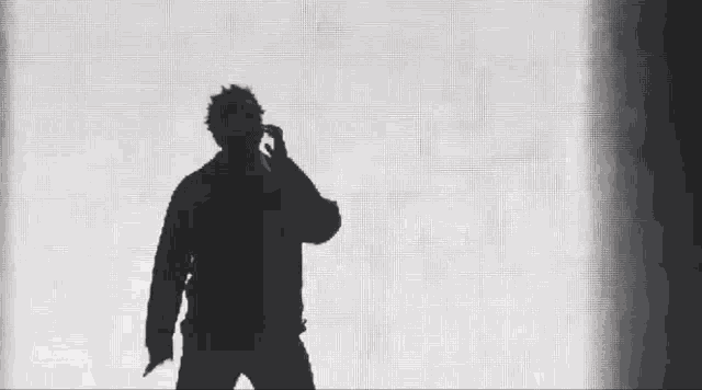 a silhouette of a man standing in front of a white wall .