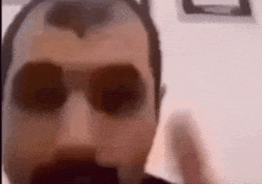 a man wearing sunglasses and a mustache is making a funny face .