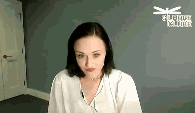 a woman wearing headphones is sitting in front of a wall that says glmo club