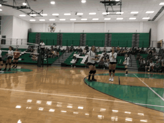 a volleyball game is being played in a gym with bleachers in the background