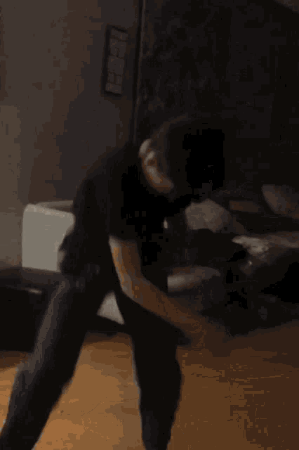 a person in a black shirt and purple pants is dancing in a room .