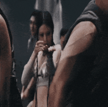 a woman in a crop top is standing in a crowd of people .